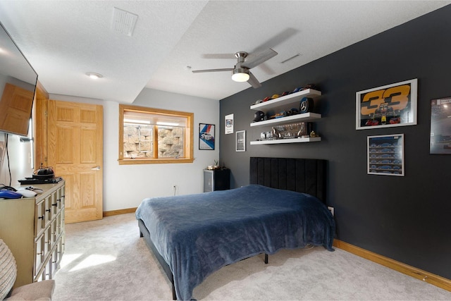 bedroom featuring visible vents, baseboards, light carpet, a textured ceiling, and a ceiling fan