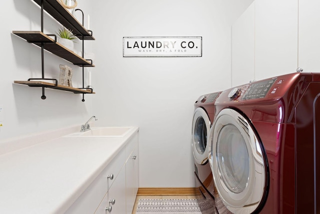 laundry room featuring washer and dryer, cabinet space, baseboards, and a sink