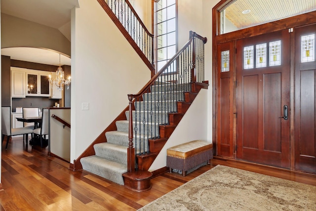 foyer with a towering ceiling, wood-type flooring, and a chandelier