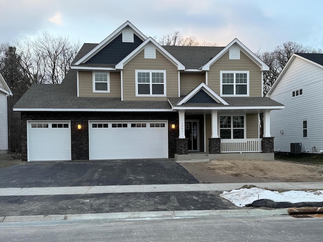 craftsman inspired home with a garage, a porch, and central air condition unit