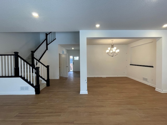 interior space featuring a textured ceiling, wood-type flooring, and a chandelier