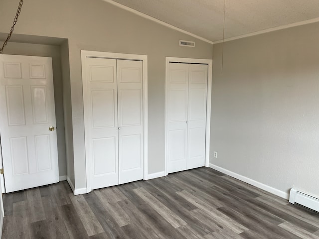 unfurnished bedroom with lofted ceiling, crown molding, multiple closets, a baseboard radiator, and dark hardwood / wood-style flooring