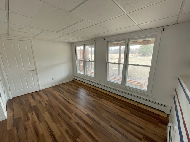 empty room featuring dark hardwood / wood-style floors, a paneled ceiling, and a baseboard radiator