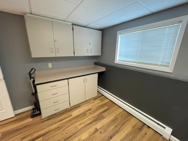 kitchen with light hardwood / wood-style flooring, a paneled ceiling, white cabinets, and baseboard heating