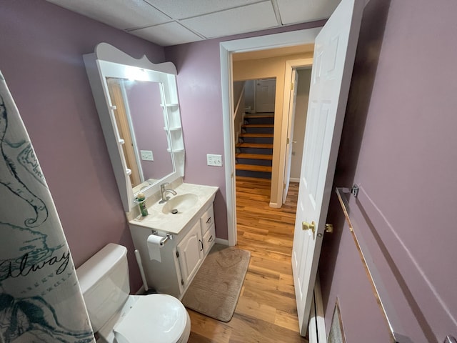 bathroom with wood-type flooring, toilet, a drop ceiling, and vanity