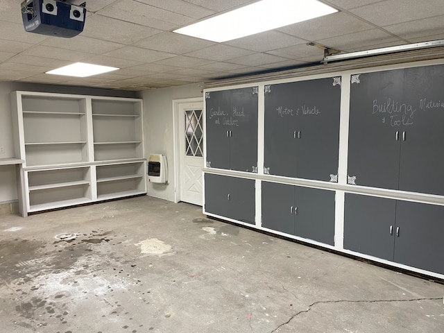 interior space with heating unit, concrete floors, and a drop ceiling