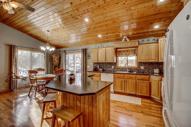kitchen with dark countertops, a sink, wooden ceiling, white appliances, and light wood-style flooring