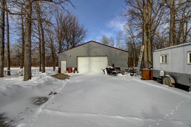 view of snowy exterior featuring a detached garage and an outdoor structure