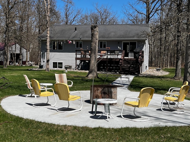 rear view of property featuring a lawn, a patio area, a fire pit, and a deck