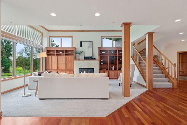 living room featuring a tiled fireplace, crown molding, and light hardwood / wood-style floors