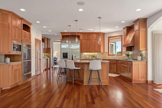 kitchen featuring sink, appliances with stainless steel finishes, hanging light fixtures, a kitchen breakfast bar, and a kitchen island