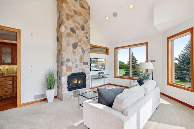 carpeted living room with a stone fireplace and high vaulted ceiling