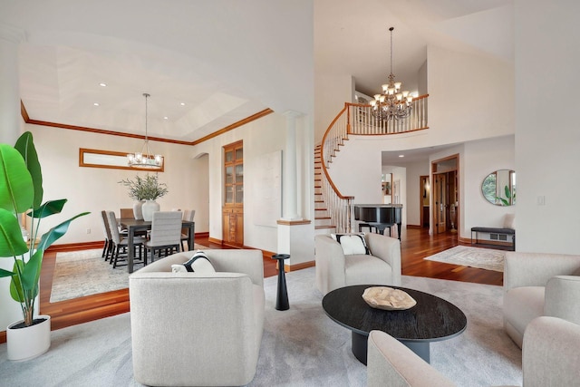 living room with a notable chandelier, a towering ceiling, decorative columns, and hardwood / wood-style flooring