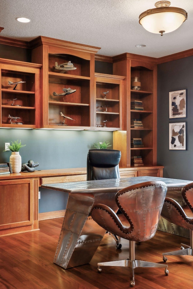 office with dark hardwood / wood-style flooring, built in desk, ornamental molding, and a textured ceiling