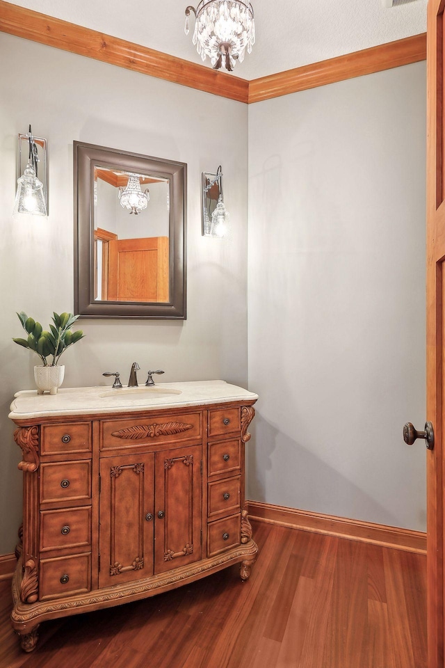 bathroom with vanity, ornamental molding, hardwood / wood-style floors, and a chandelier