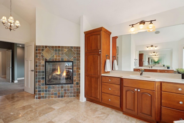 bathroom featuring lofted ceiling, vanity, a fireplace, and a chandelier