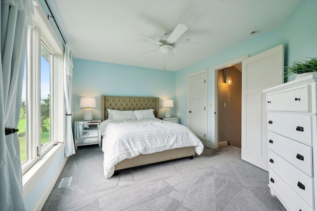 carpeted bedroom featuring multiple windows and ceiling fan