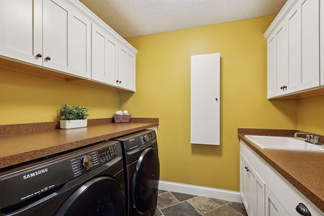 laundry area featuring cabinets, sink, a textured ceiling, and washer and clothes dryer