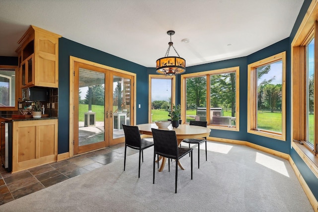 dining area with an inviting chandelier, dark carpet, and french doors