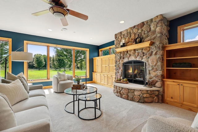 carpeted living room with ceiling fan and a fireplace