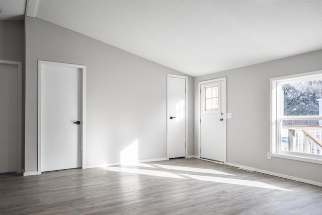 spare room featuring vaulted ceiling, hardwood / wood-style floors, and a textured ceiling