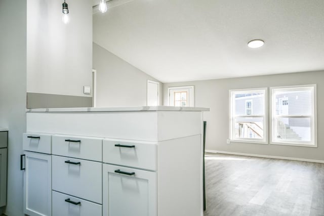 kitchen featuring lofted ceiling, white cabinets, and light hardwood / wood-style floors