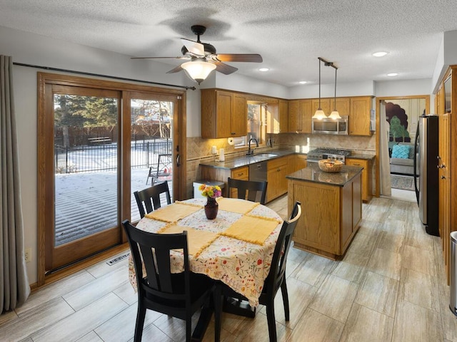 dining space featuring sink, a textured ceiling, a healthy amount of sunlight, and ceiling fan