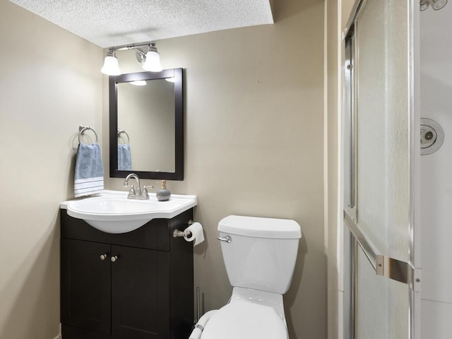 bathroom with vanity, toilet, and a textured ceiling