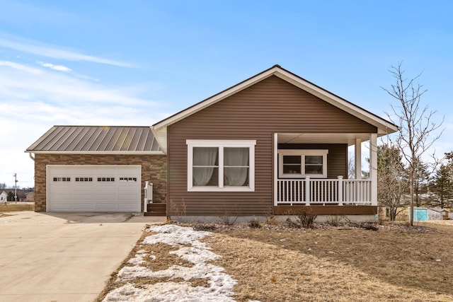 view of front of home with a porch, concrete driveway, metal roof, and an attached garage