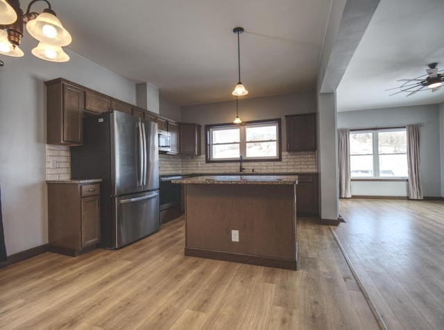 kitchen with light wood finished floors, decorative backsplash, appliances with stainless steel finishes, a sink, and dark brown cabinets