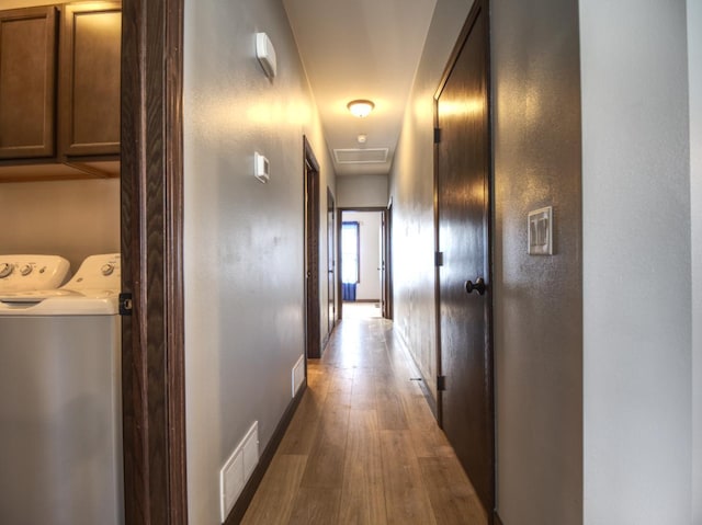 corridor with wood finished floors, visible vents, baseboards, and separate washer and dryer