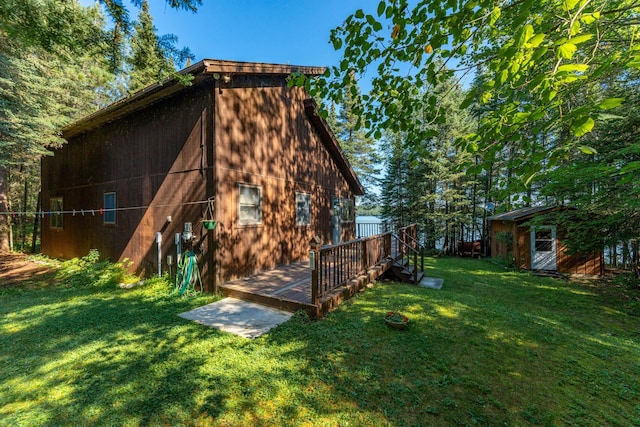 back of house with a wooden deck, a yard, and an outbuilding