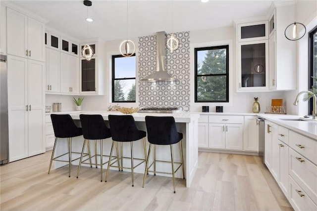 kitchen with sink, pendant lighting, white cabinets, and light wood-type flooring