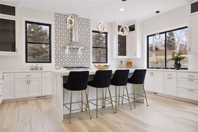 kitchen featuring pendant lighting, white cabinetry, light hardwood / wood-style floors, and a center island