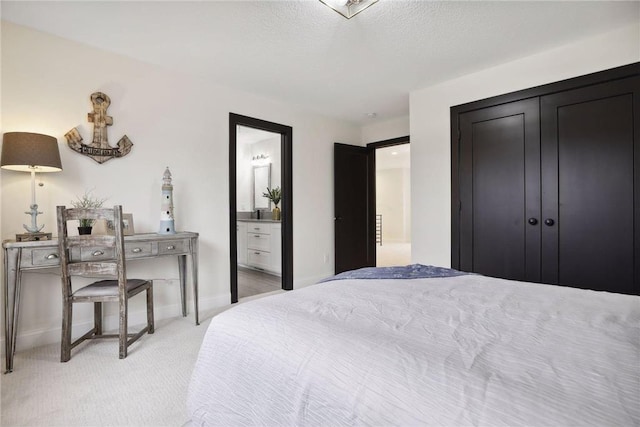 carpeted bedroom featuring ensuite bathroom, a closet, and a textured ceiling