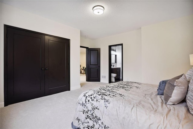 carpeted bedroom featuring ensuite bathroom, a textured ceiling, and a closet