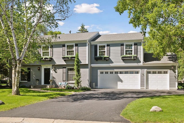 view of front of home with brick siding, a garage, aphalt driveway, and a front yard