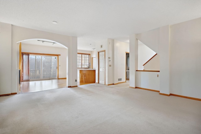 unfurnished living room with light colored carpet and a textured ceiling