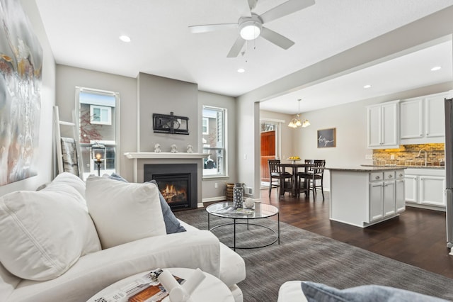 living room with sink, ceiling fan with notable chandelier, dark hardwood / wood-style floors, and a healthy amount of sunlight