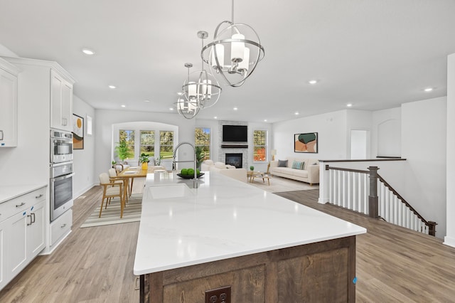 kitchen with a spacious island, sink, hanging light fixtures, and white cabinets