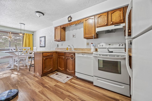 kitchen with sink, white appliances, a textured ceiling, decorative light fixtures, and light wood-type flooring