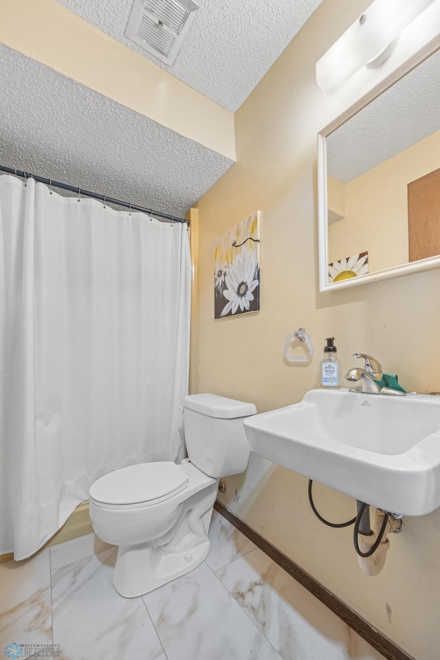 bathroom with toilet and a textured ceiling