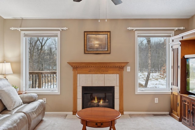 carpeted living room with a tile fireplace and ceiling fan