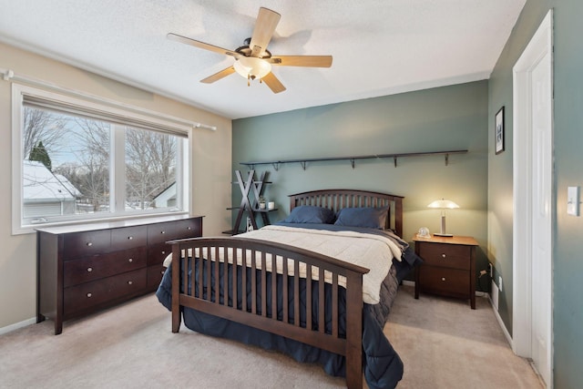 bedroom featuring a textured ceiling, light colored carpet, and ceiling fan