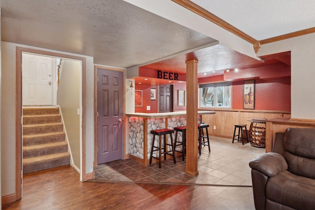 kitchen with ornate columns, ornamental molding, hardwood / wood-style flooring, and wood walls