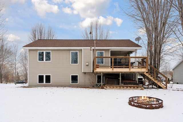 snow covered back of property featuring a deck and a fire pit