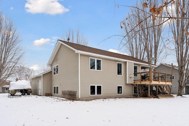 snow covered back of property featuring a wooden deck