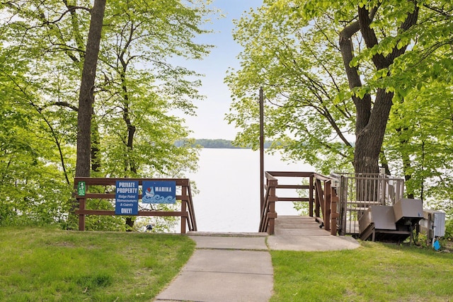 view of dock with a water view and a yard