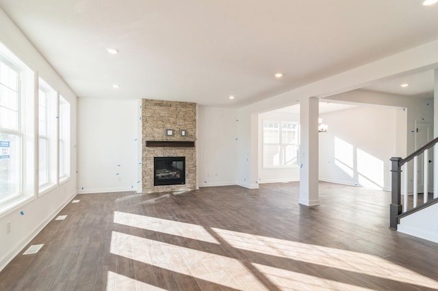 unfurnished living room featuring an inviting chandelier, a fireplace, and dark hardwood / wood-style floors