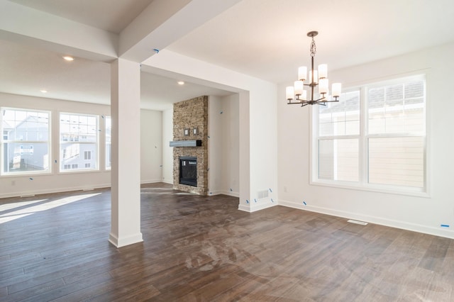 unfurnished living room featuring an inviting chandelier, a fireplace, and dark hardwood / wood-style floors